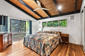 A bedroom with a wooden ceiling, a bed with a patterned bedspread, a nightstand, a TV on a wooden cabinet, and a window with a view of greenery. - Sandy Paws 
Toogoom 
Beachfront (Toogoom)