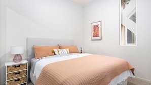 Ein Schlafzimmer mit einem Bett, einem Nachttisch, einer Lampe und einem gerahmten Bild an der Wand.