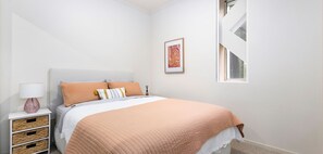 A bedroom with a bed, bedside table, lamp, and a framed picture on the wall. - Bright 2-bedroom apartment with AC in charming Southbank (Southbank)