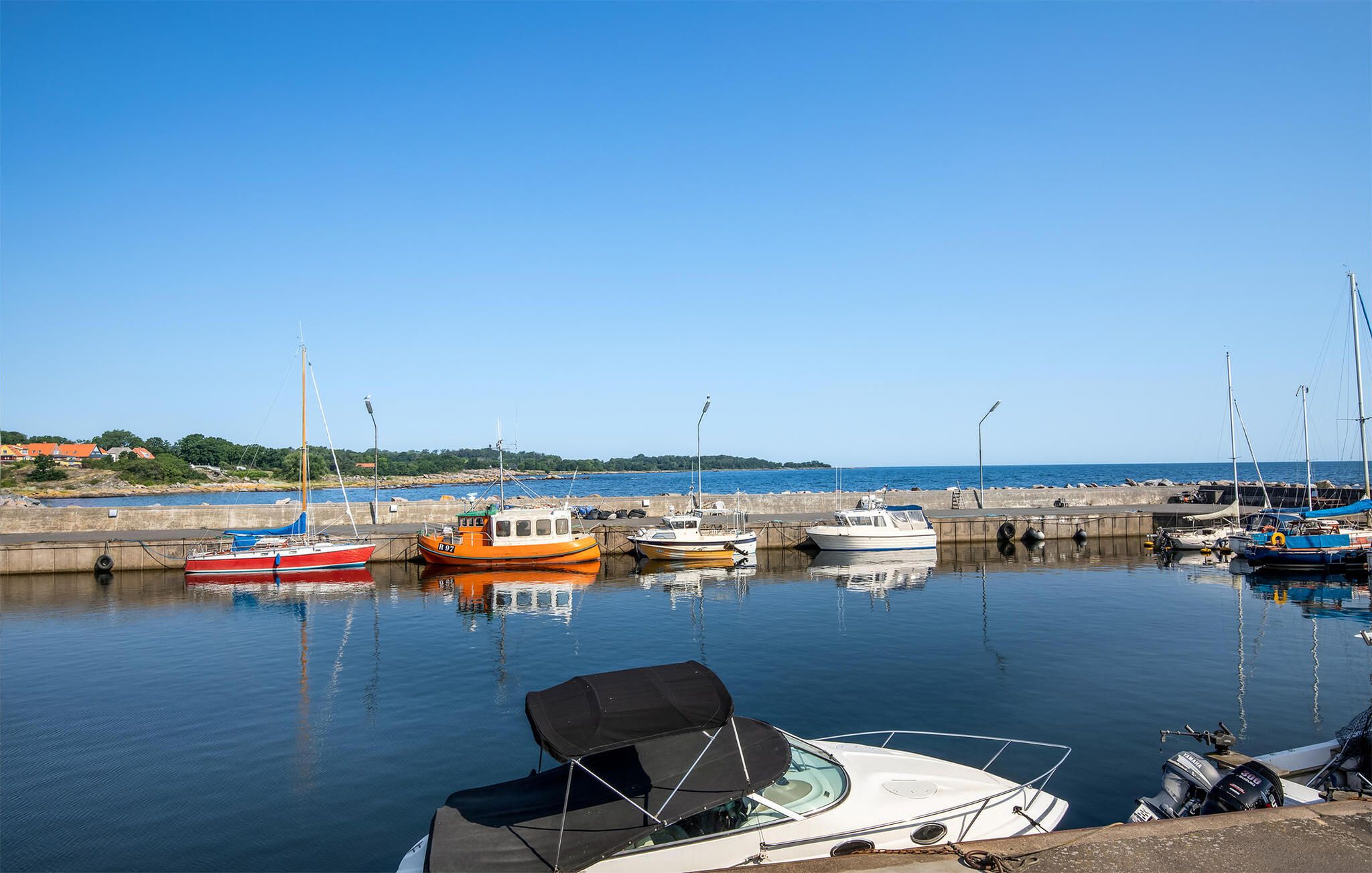 En lystbådehavn med forskellige både i havnen, stille vand og en klar himmel.