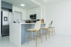 Eine moderne Küche mit Kochinsel, Edelstahlgeräten und Holzbarhocker.