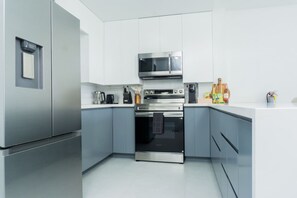 A modern kitchen with stainless steel appliances, grey cabinets, and a white countertop. - Azure 6th Floor Luxury 2bdrm Condo Walk to Beach (Ocho Rios)