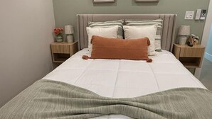 A neatly made bed with a white comforter and a green knitted throw. There are two framed pictures on the wall above the bed. - Sunrise at Sarasota (Sarasota)