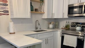 A kitchen with white cabinets, a stainless steel oven, a microwave, and a bar stool area. - Sunrise at Sarasota (Sarasota)