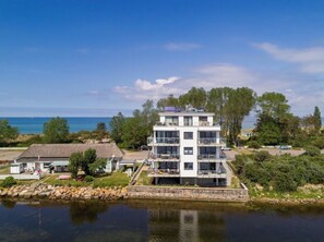 A modern multi-story building with balconies, situated by a body of water with a clear view of the sea. - House Kiki, Apartment 6 "ocean View" (Heiligenhafen)
