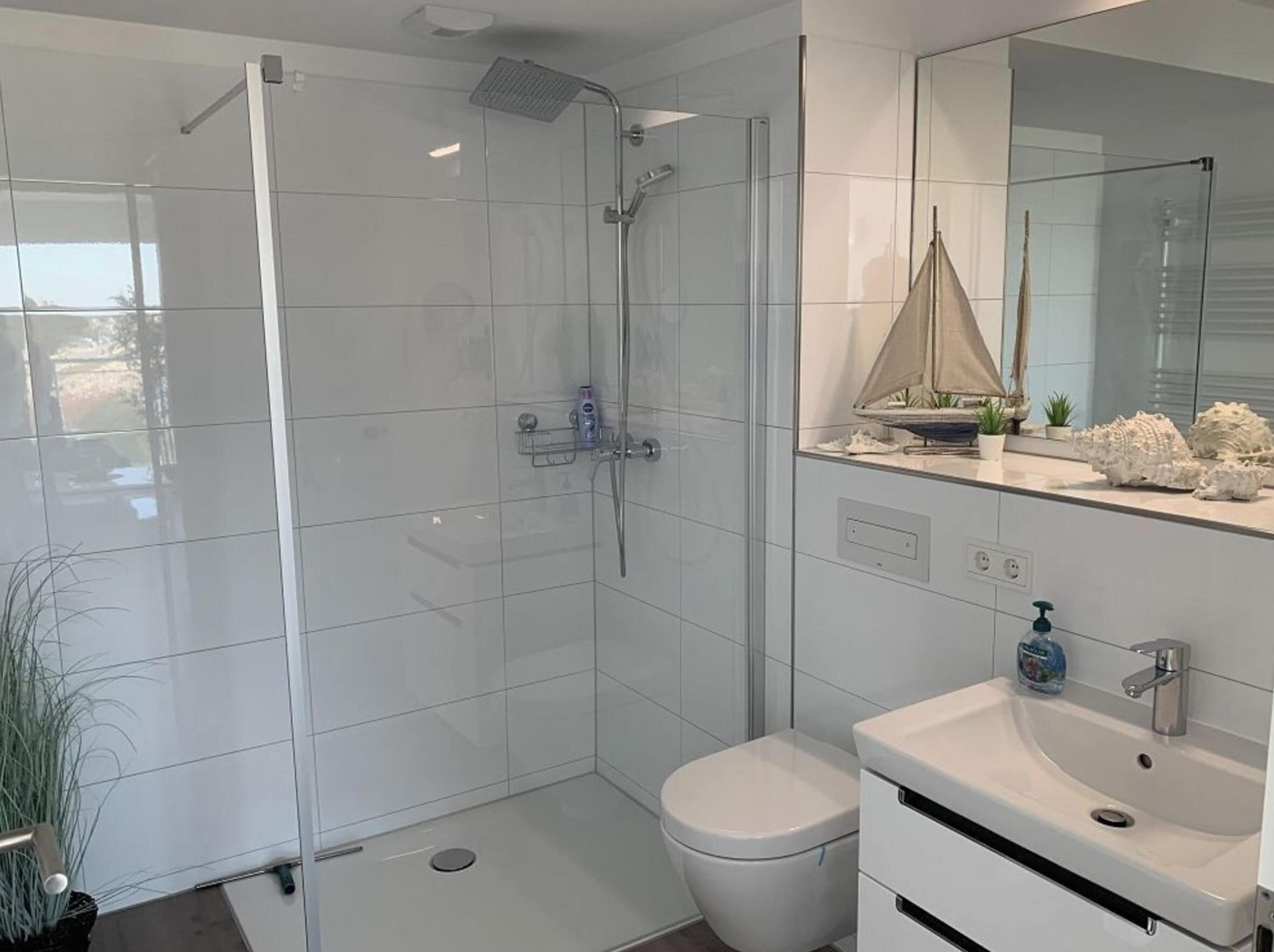 Un bagno moderno con doccia vetrata, un water bianco e un lavabo con specchio sopra.