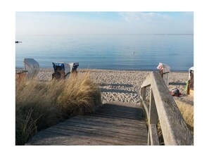 A wooden boardwalk leading to a sandy beach with beach chairs and a flag. - House Kiki, Apartment 6 "ocean View" (Heiligenhafen)