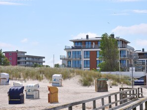 A beachside building with multiple balconies and a sandy foreground with beach chairs. - Holiday Apartment With 2 Bedrooms (Heiligenhafen)
