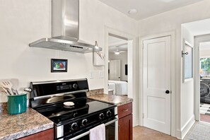 A kitchen with a black stove, stainless steel range hood, and granite countertops. - Cutest 3 BR cottage in New Bern close to everything! Welcome to the New Bernian! (New Bern)