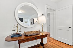 A wooden console table with a round mirror, a lamp, and a scale. - Cutest 3 BR cottage in New Bern close to everything! Welcome to the New Bernian! (New Bern)