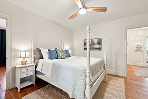 A four-poster bed with a ceiling fan, a nightstand with a lamp, and a patterned rug. - Cutest 3 BR cottage in New Bern close to everything! Welcome to the New Bernian! (New Bern)