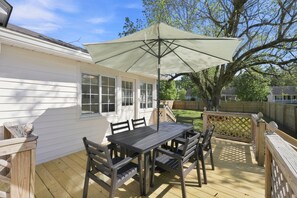 A patio with a table and chairs, a large umbrella, and a wooden deck. - Cutest 3 BR cottage in New Bern close to everything! Welcome to the New Bernian! (New Bern)