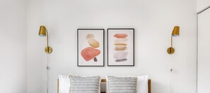 Ein Schlafzimmer mit einem Bett, zwei Kissen und zwei gerahmten Kunstwerken an der Wand.