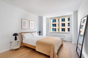 A bedroom with a bed, a window, and a radiator. - Blueground | Manhattan, rooftop, nr Freedom Tower (New York)
