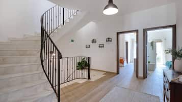 A modern interior with a spiral staircase, wooden flooring, and a view into another room.
