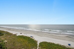 A beach with a clear sky, a sandy shore, and a few people walking. - San-A-Bel Oceanfront Getaway | 2BR (North Myrtle Beach)