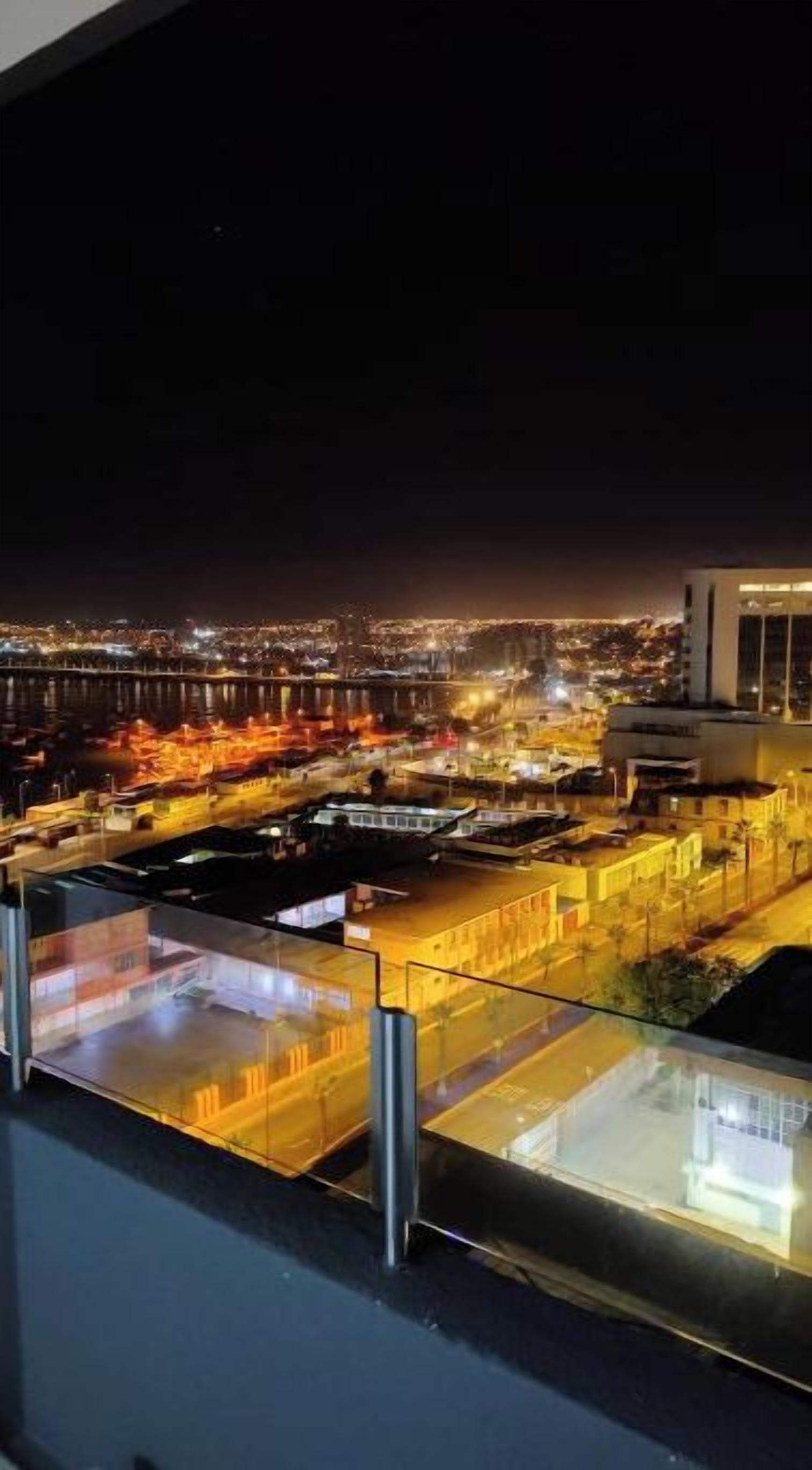 A nighttime cityscape with a view of a bridge and illuminated buildings.