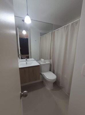 A small bathroom with a toilet, sink, and mirror. - Apartment with an ocean view across from the harbor/downtown (Coquimbo)