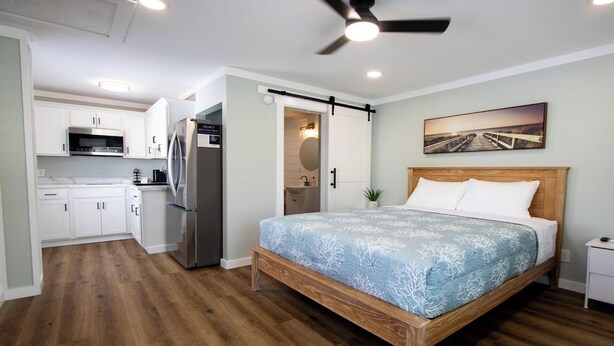 A bedroom with a bed, a ceiling fan, and a painting on the wall. - ⚓ Brand New Downtown Retreat: The Lofts at Big Rock Landin (Morehead City)