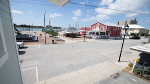 A street view with a red building, a parking lot, and a body of water in the background. - ⚓ Brand New Waterfront Retreat: Unit 3 at The Lofts at Big Rock Landing (Morehead City)