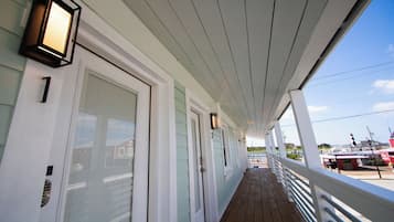 A covered porch with a railing, doors, and exterior lighting fixtures.