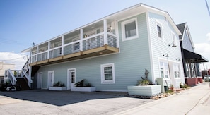 A two-story building with a balcony on the upper floor, a visible staircase, and a small garden area with plants. - ⚓ Brand New Waterfront Retreat: Unit 4 at The Lofts at Big Rock Landing (Morehead City)