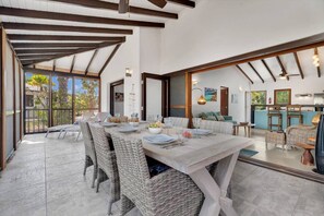 A dining area with wicker chairs, a marble table, and a view of the outdoors. - Casa Divers Dream - Screened porch and shared pool! (Kralendijk)