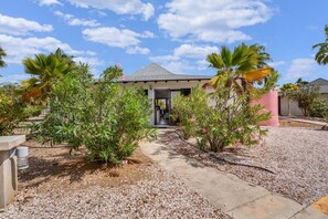 A building with a gravel driveway, palm trees, and a clear sky. - Casa Divers Dream - Screened porch and shared pool! (Kralendijk)