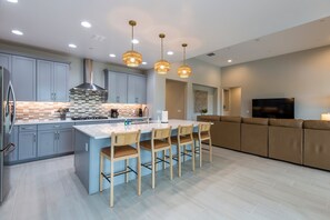Una cocina moderna con una isla central, armarios grises e iluminación colgante.