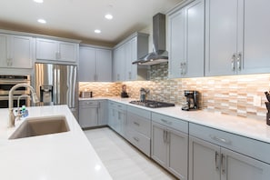 A modern kitchen with stainless steel appliances, a large island, and a patterned backsplash.