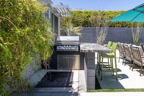 An outdoor patio with a built-in grill, seating area, and a view of a mountain. - Flamingo Oasis | Private Pool & Spa | Firepit | Sleeps 6 (Palm Springs)