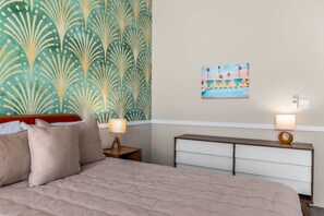 A hotel room with a bed, a nightstand, a lamp, a painting on the wall, and a view of a pool. - Flamingo Oasis | Private Pool & Spa | Firepit | Sleeps 6 (Palm Springs)