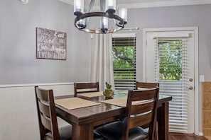 A dining area with a wooden table and chairs, a chandelier, a decorative sign, and a window with blinds. - Horizon Hideaway | Balcony | Pool & Spa | North Scottsdale (Scottsdale)