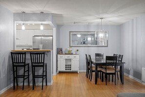A modern kitchen with white cabinets, a dining area with a wooden table and black chairs, and a pendant light above the table. - Scottsdale Buena Terra 🌵⛳ Pool, Hot Tub & Game Room Near Old Town Scottsdale (Scottsdale)
