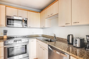 A modern kitchen with stainless steel appliances, granite countertops, and wooden cabinets. - Blueground | Fenway–Kenmore, gym, nr Fenway Park (Boston)
