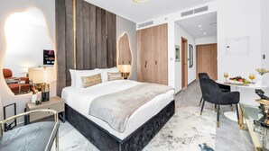Ein modernes Hotelzimmer mit einem großen Bett, Nachttischen, einem Schreibtisch und einem Sessel.