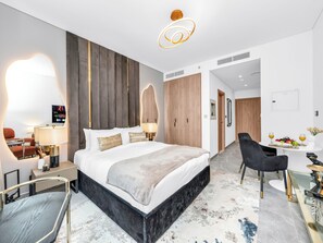 Moderni hotellihuone, jossa on suuri sänky, yöpöydät, työpöytä ja tuoli.