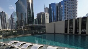 Ein Pool auf dem Dach mit Liegestühlen und Blick auf die Stadt.