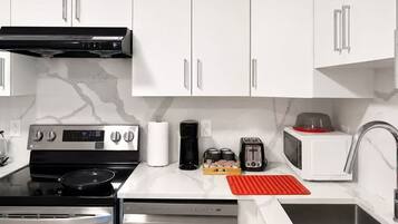 A modern kitchen with white cabinets, stainless steel appliances, and a marble backsplash.