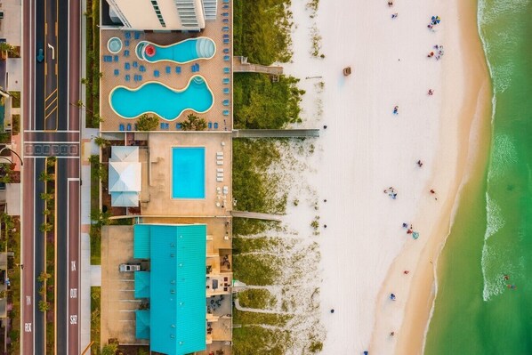 A resort with a pool area, beach, and a building with a blue roof.