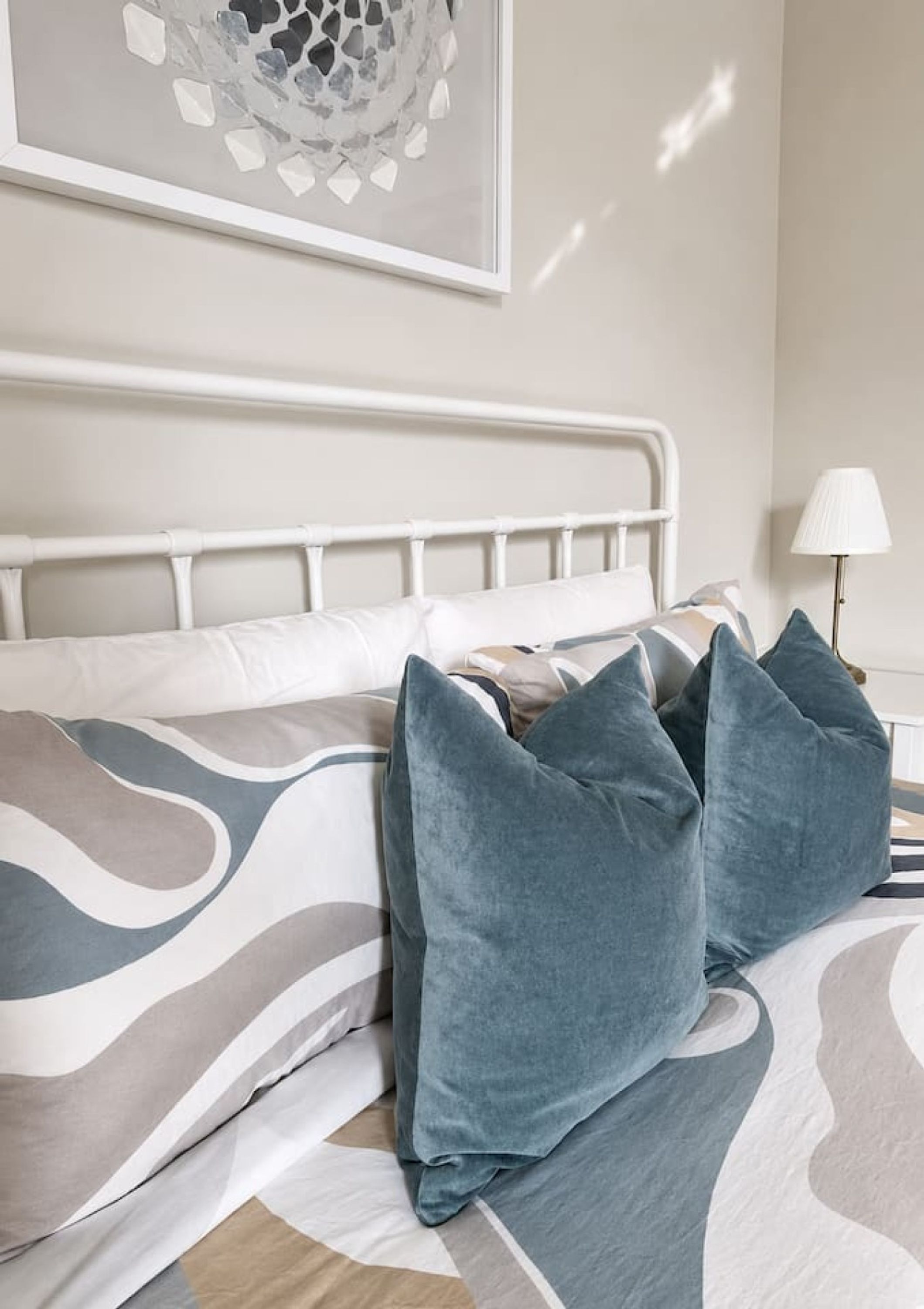A bed with a white metal frame, a patterned bedspread, and several pillows.