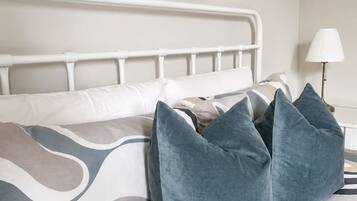 A bed with a white metal frame, a patterned bedspread, and several pillows.