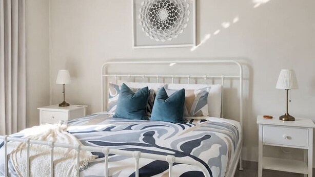 A bedroom with a bed, bedside tables, a ceiling fan, and a wall-mounted artwork. - 2BR 10 Min Walk to Beach Private Rooftop BBQ (Punta Cana)
