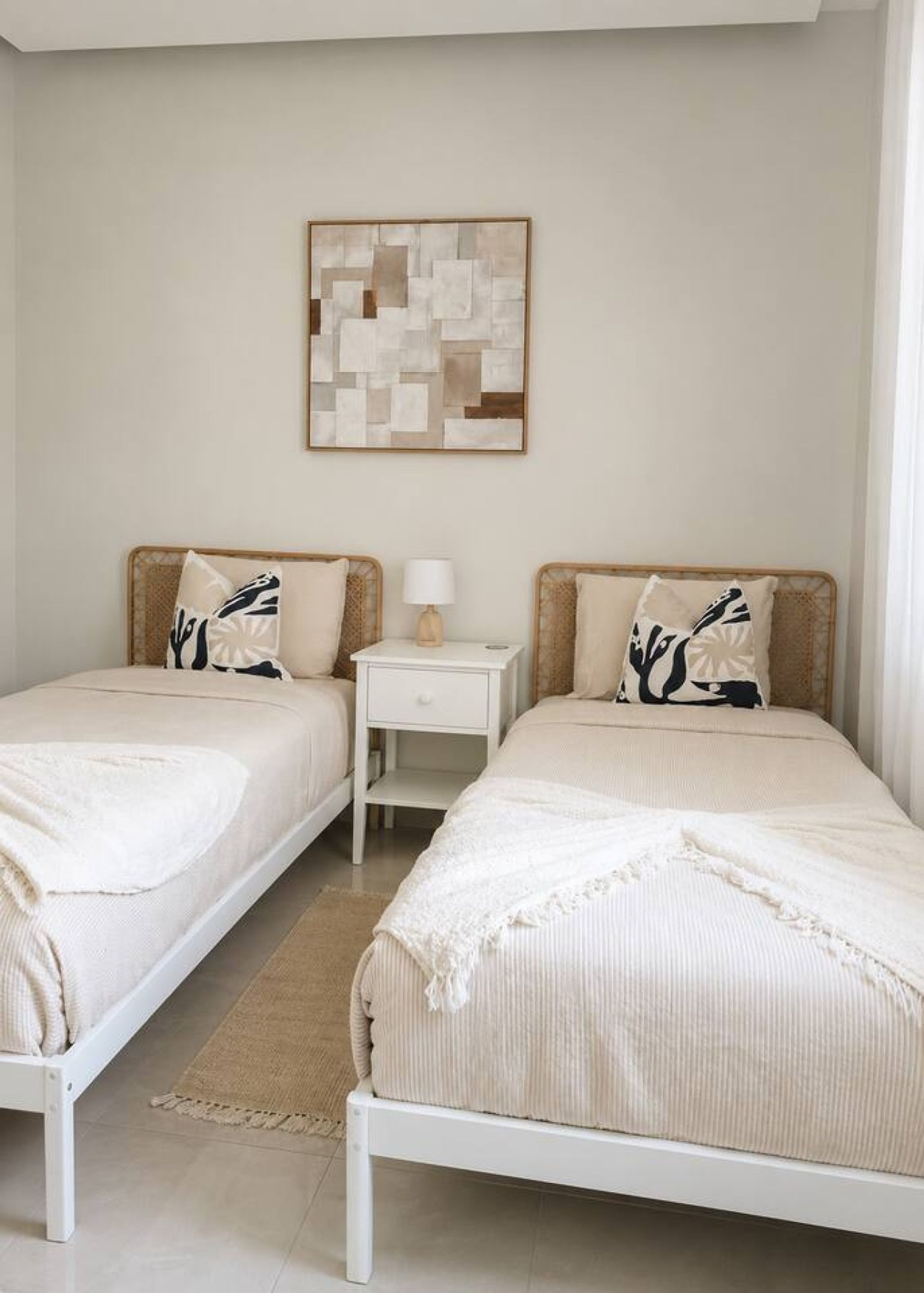 Quarto com duas camas de solteiro, mesa de cabeceira, luminária e uma obra de arte na parede.