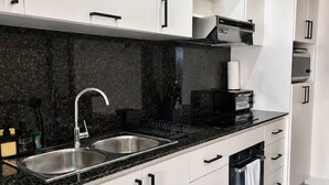 A modern kitchen with white cabinets, black countertops, and stainless steel appliances. - 2BR 10 Min Walk to Beach Private Rooftop BBQ (Punta Cana)