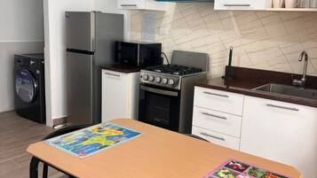 Una cocina moderna con armarios blancos, una campana extractora azul, un refrigerador de acero inoxidable, un microondas, una estufa a gas y un lavavajillas.