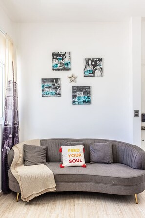 A modern living room with a grey sofa, a throw blanket, and a pillow with motivational text. - Cozy 1BR 1 Min Walk to Beach Pool BBQ Area (Punta Cana)