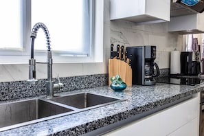 A kitchen with a double sink, a coffee maker, and a knife block. - Cozy 1BR Beach Pool Electricity Included (Punta Cana)