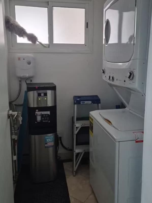 A compact laundry room with a water heater, a washing machine, and a drying machine. - 2BR Beachfront Penthouse Private Rooftop Terrace (Punta Cana)