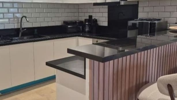 Una cocina moderna con una isla central, encimeras negras y armarios blancos.